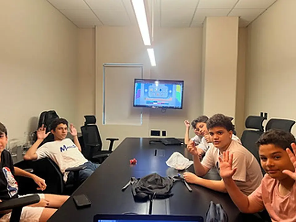 Alunos acenando ao redor da mesa durante uma aula na Wind Connection